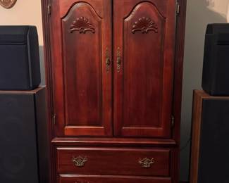 Traditional Wood Media Chest  Tall wood media chest featuring two cabinet doors with decorative carved details and three spacious lower drawers with brass-style hardware. This piece offers plenty of storage for electronics, media, clothing, linens, or household items.