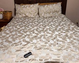 Elegant queen-size bed featuring a tall, dark wood headboard with decorative carved panel details. The rich finish gives it a traditional, upscale look that works well in a primary bedroom or guest room.