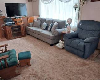 glider rocker, Lazyboy recliner, gray couch, side tables, TV stand, pole lamp, globe lamp, 47” LG TV, DVD player, VHS player, boom box, old style radio