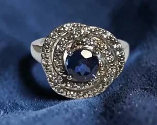 Sterling ring with central blue stone surrounded by a swirling halo