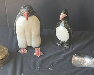 Lot 48: Assorted decorative items including penguin figurines, an ornate tin, a jewelry box with knotted bracelets, a glass sculpture, and round coasters