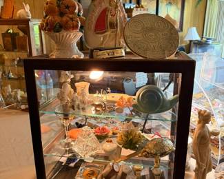 This showcase contains, Van Briggle snail, Poodles, Men's vintage watches, ceramics, porcelains, vintage Jim Bean, Franciscan plate