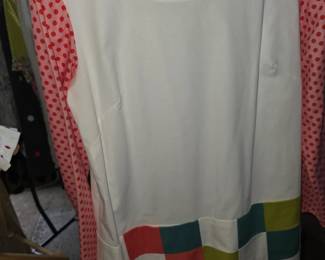 This white dress features a vibrant checkerboard pattern hem and contrasting red polka dot long sleeves.
