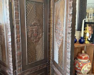 Antique room divider with dark-stained wood panels with geometric carvings 