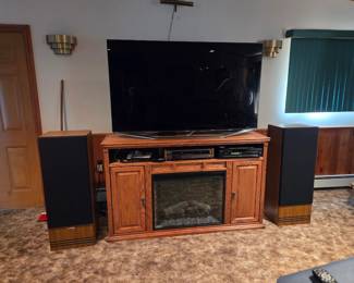 golden oak electric fireplace media console featuring a central electric heater insert flanked by side storage cabinets and upper component shelves
