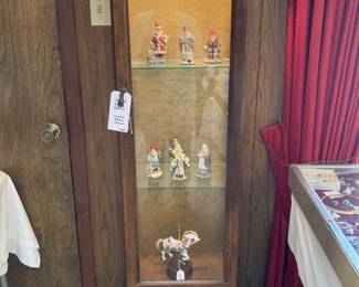narrow lighted display cabinet with International Santas and musical carousel