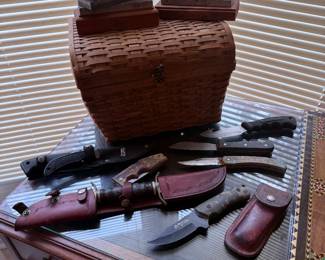Hunting knives, fixed blade knives, leather sheaths, woven basket, and wooden boxes.