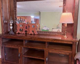 Large solid wood entertainment center with mirror, storage cabinets, open shelving, and rustic traditional design.
