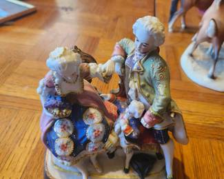 Vintage Hand-Painted Porcelain Rococo Family Figurine  Elegant vintage porcelain figurine featuring a finely detailed 18th-century Rococo couple with a young child. Beautifully hand-painted in vibrant colors with raised floral decorations and gold gilt trim. A wonderful decorative piece for collectors of European-style porcelain, Victorian décor, or vintage figurines.  Manufacturer: Unknown (maker's mark not visible) Approximate Year: 1950s–1970s Material: Glazed porcelain with hand-painted and gilt accents Condition: Good vintage condition with normal wear from age. No major damage visible from the front (inspect for chips or repairs before listing). Style: Rococo / Victorian Revival / Courtship Scene Suggested Estate Sale Price Quick Sale: $20–30