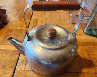 Vintage Stainless Steel Tea Kettle with Wood Handle  Classic vintage stainless steel tea kettle featuring a timeless rounded design with a wood handle and matching wood lid knob. A functional and decorative kitchen piece perfect for everyday use, farmhouse décor, cabin kitchens, or collectors of mid-century housewares.  The kettle has a polished stainless steel body with natural patina from age and use, adding to its authentic vintage character. Great for display or continued use.  Features:  Vintage stainless steel construction Wood carry handle Matching wood lid knob Traditional stovetop design Mid-century style  Approximate Year: 1950s–1970s  Condition: Good vintage condition with light scratches and age-related wear consistent with normal use. Clean interior. Please review all photos for condition.  Estate Sale Price  $25.00  Shipping  Buyer pays actual shipping. Local pickup is also available.