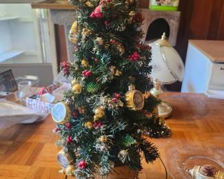 Lighted Christmas Tree Holiday Decoration  Price: $35  Decorative lighted Christmas tree with ornaments, star topper, and illuminated winter village base. A beautiful tabletop holiday decoration.  Condition: Good vintage condition with light wear. Includes power adapter. Sold as found; see photos.  Estimated Value:  Estate Sale: $35 Online: $45–70 Antique Shop: $65–90  Buyer pays shipping or local pickup available.