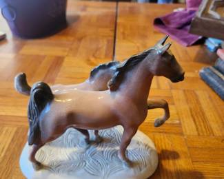 Vintage Porcelain Horse Figurine – Hand Painted Equestrian Statue  Beautiful vintage porcelain horse figurine featuring a bay horse with black mane and tail in a spirited pose on a textured white base. Hand-painted with fine detailing, this decorative equestrian piece makes a great addition to a horse collection, curio cabinet, or Western-inspired décor. A timeless display piece for horse enthusiasts and vintage porcelain collectors.  Manufacturer: Unknown (original foil label partially missing) Approximate Year: 1950s–1970s Material: Glazed porcelain Condition: Good vintage condition with normal age-related wear. No major chips or cracks visible. Please review photos for overall condition. Suggested Estate Sale Price Quick Sale: $15–20 Middle-of-the-Road Price: $30 Retail/Collector Price: $40–50 if in excellent condition. Shipping  Buyer pays actual shipping. Local pickup is also available.