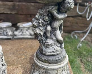 Concrete cherub holding bowl on pedestal