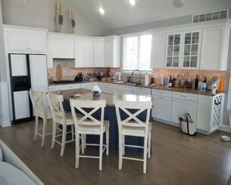 Crisp white kitchen with plenty of upper & lower cabinets; navy island. 4 bar stools by Century Furniture