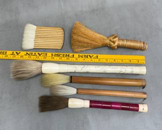 A vintage decorative Chinese calligraphy brush featuring an etched bone-style handle and natural horsehair bristles; traditional flat wash or hake brushes with bamboo handles;a multi-head bamboo hake brush; and a small, handmade natural fiber whisk broom featuring a braided knot and wrapped handle design