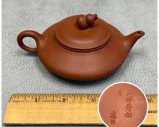 A vintage Chinese unglazed Yixing zisha teapot with a flattened "oil lamp" or drum shape and double-gourd lid finial; marked to the base with line from Tang dynasty poem, and apocryphal  Huì Yìgong mark. 