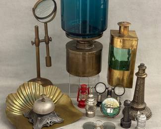 A vintage adjustable brass desktop magnifying glass on a swiveling stand; a Scandinavian modernist L47 oil lamp by Hans Agne Jakobsson Markaryd AB, Sweden; a musical decanter ship stern light green glass bottle made in Sweden; an antique Jugendstil (Art Nouveau) silver-plated mechanical desk call bell manufactured by A.K. & Cie (Albert Köhler & Cie, Germany) circa 1900; antique C-bridge pince-nez sunglasses featuring dark-tinted oval glass lenses and metallic spring-tension nose bridges from the late 19th to early 20th century