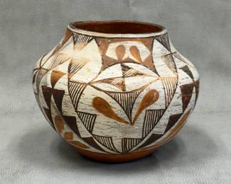 An historic Native American Pueblo polychrome pottery vessel, likely an Acoma or Laguna pueblo olla from the early-to-mid 20th century, featuring hand-painted geometric patterns and stylized floral elements over a white slip; approximately 6-3/4 inches tall