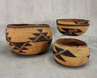 A northern California Native American (possibly Hupa, Yurok or Karuk) large twined basket with geometric designs of stepped triangular motifs and linear bands, approx 9-3/4”W x 6”H; an Indigenous peoples of Northern California traditional twine-woven basket cap or hat with stacked geometric zigzag elements on the side and repeating at the rim above a black and brown band, approx 7”W x 4”H; and a Shagton Group Pit River California woven natural fibers basket with pattern frequently interpreted as representation of geese in flight or stacked flint blades; approx 7” wide