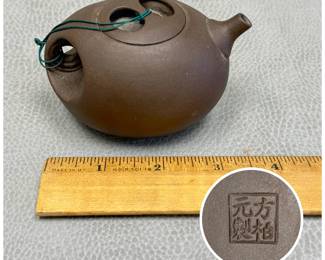 A  Fang Baiyuan Yixing style clay tea pot featuring a unique horizontal side-hole handle and a flush lid tied with a green string; maker's mark to base