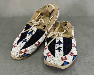 Pair of vintage/antique Plains Indian glass beaded leather moccasins, likely Cheyenne or Lakota Sioux; soft buckskin or hide hand-sewn with intricate geometric lane-stitched beadwork in black, white, red, and blue