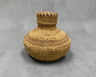 A small, tightly coiled basketry jar with a matching lid, featuring natural tan and darker brown plant fibers woven in a banded geometric pattern; 4-1/4" tall