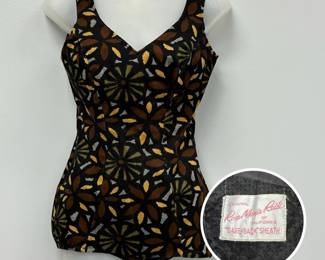 A 1950s vintage Rose Marie Reid “Dare-Back” Sheath one-piece swimsuit in a black, brown, green, and gold abstract floral print; 2 button adjustable straps and built-in underwire bra. Two interior labels, the first reads Original Rose Marie Reid of California “Dare-Back” Sheath and the second label says Rose Marie Reid Circolair bra.