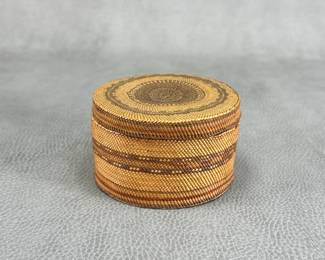 A Northwest Coast Native American small lidded circular basket with concentric geometric patterning and tight coiled construction; 4 inches wide.