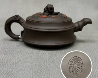 A dark brown Yixing Zisha purple clay teapot decorated with branch-form handle and spout, and embossed flower and branch details on the lid