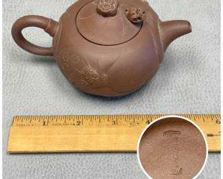 Closer view of the Yixing teapot in "Fish Transforms into Dragon Pot" design with a fish among waves on the side of the pot and articulated dragon's head in the lid beneath a cloud shaped finial; maker's mark to the base
