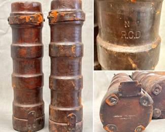 Pair of antique cylindrical cordite carriers, 23-1/2" tall. The main body of the bucket is made of cork with a brown leather exterior and canvas interior. Stamped with R.C.D. on the side, and “country of origin England” on the base. These flash proof carriers were designed to transfer cordite, a group of smokeless propellants developed and produced in the United Kingdom to replace gunpowder as a military propellant.