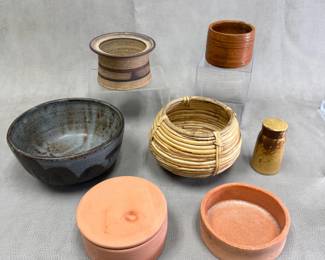 Glazed and unglazed artisan pottery vessels and a vintage handwoven small round rattan storage basket