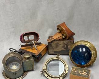 A brass ship's binnacle compass equipped with a side-mounted oil lamp burner; an antique wooden and cast-iron guillotine-style paper cutter; an antique handheld stereoscope viewer, wooden lens hood trimmed with velvet or plush fabric; an antique wooden and brass handheld stereoscope Graphoscope stereo viewer;