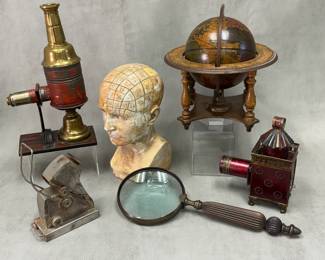 Antique magic lanterns; an antique phrenology bust; an antique or vintage handheld brass magnifying glass; a decorative desktop world globe featuring an antique-style map and a zodiac horizon ring