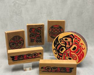 A collection of handcrafted Pacific Northwest Coast Indigenous wooden boxes and bentwood boxes featuring traditional formline designs in black and red pigment