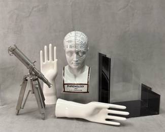 A white porcelain L.N. Fowler phrenology head statue; a nautical-style decorative desktop telescope / spyglass on metal tripod with extendable legs, and a small decorative chain attached to the end cap; and two vintage or antique porcelain industrial glove molds
