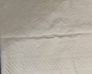 vintage white matelassé or piqué bedspread, featuring intricate woven floral and textured decorative patterns