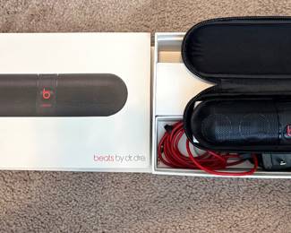 a Beats by Dr. Dre Pill 2.0 portable wireless speaker in black.It includes a soft carrying case and a red charging cable