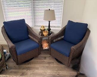 brown wicker chairs with navy cushions appear to be part of a 2-piece swivel rocker set from Joyside or PremDwell.
