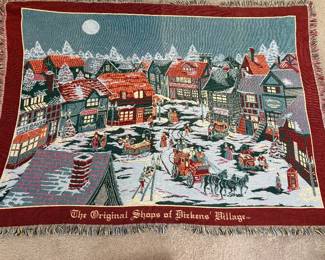 Dept 56 woven tapestry throw blanket, titled "The Original Shops of Dickens' Village," features a snowy Victorian town scene with a horse-drawn carriage
