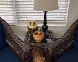 brown wicker chairs with navy cushions appear to be part of a 2-piece swivel rocker set & matching accent table from Joyside or PremDwell.