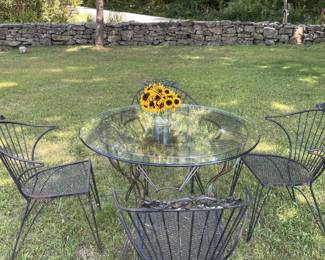 outdoor iron table with round glass top and four matching chairs