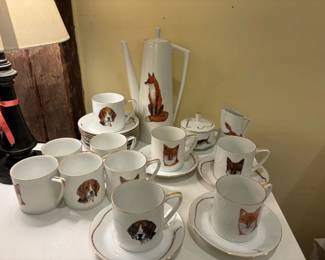 Hand painted hunt themed china coffee/tea service by PF Menzies : 11 saucers with hunt whips, 10 cups with half hounds and half foxes, tall pitcher with lid with fox on one side, hunt whip on the other, lidded sugar bowl with 3 hounds, small cream pitcher with fox and tree and fence on back