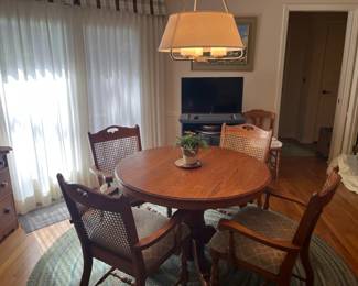Solid oak pedestal dining set with four matching cane-back armchairs