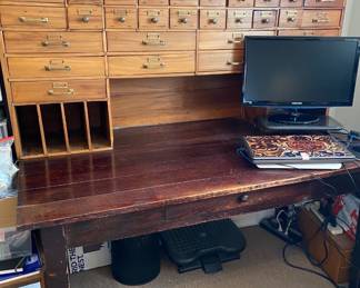 Massive Pine Cabinet with 39 Drawers and vertical slots on the left, and horizontal slots on the right with an enclosed top great for display. Originally was from a hardware store. Sitting on a reddish Oak Vintage Library Table that has legs that unbolt.