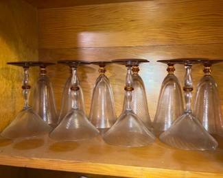 A fine set of 9 hand-blown or blown-glass stemmed cocktail glasses / martini goblets featuring clear conical bowls with subtle swirl/optic texturing, clear stems with distinct amber glass bead/knop accents, and round amber-tinted or clear bases.