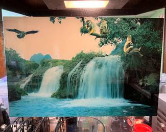 Vintage, illuminated motion waterfall picture with built-in lighting, sound effects, and revolving mechanism to create a moving waterfall effect. This item has a special motif featuring "Three Wise Monkeys" design over the the waterfall scene.