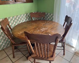 Classic round wooden dianing set featuring pedestal table and four matching spindle-back farmhouse style chairs.