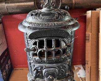 Antique cast-iron parlor stove featuring ornate scrollwork and a "BEAUTY" inscription. Manufactured in the late 19th to early 20th century.