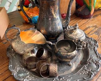 Vintage silver-plated tea set includes tea pot, sugar bowl, creamer, and ornate platter.